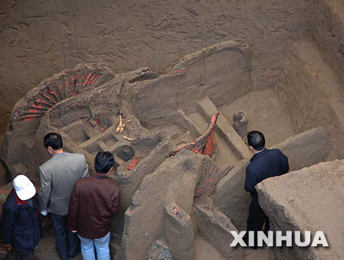 在甘肃张家川考古发掘现场,一些专家在参观出土不久的随葬车(11月15日摄)。 日前,一个大型战国时期墓葬在甘肃张家川回族自治县境内被发现。在已发掘的三个墓坑中,已清理出10辆有精美漆绘和金、银等装饰的随葬车,这些随葬车之“豪华”,为国内以往考古中所罕见。在此次考古发掘中,还发现了大量的金、银、铜、陶等随葬器物及一批兽骨。
