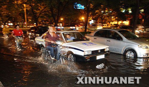 7月26日,几位西安市民在积水的道路上骑车。 当晚8时许,西安地区突降暴雨,并伴有大风和雷电。暴雨造成西安城区部分路段短时积水,西安火车站多趟列车晚点,大批旅客滞留。 新华社记者 焦卫平 摄