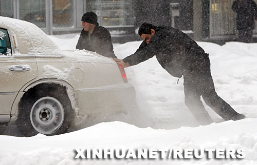 12月3日,在加拿大蒙特利尔,两名男子在雪中艰难地推车前行。