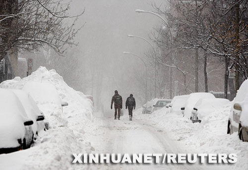 12月3日,在加拿大的蒙特利尔市,两名行人在雪中前行。