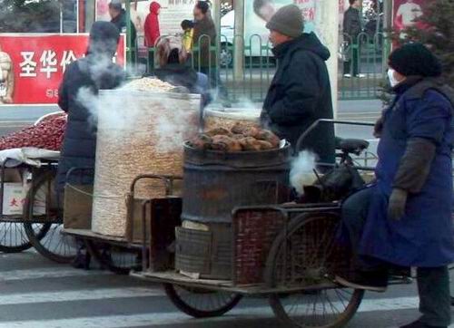 冰糖葫芦,玉米花,烤地瓜,大红枣等食品裸露在寒风中,小商小贩集聚