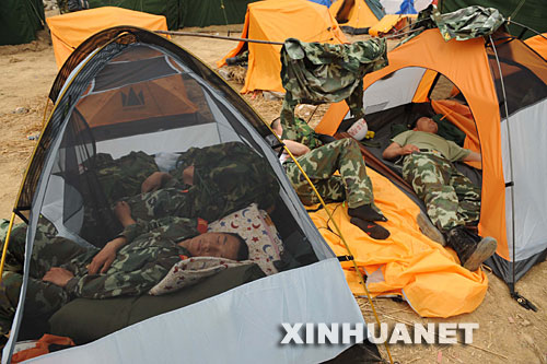5月17日,在汶川地震重灾区北川县,从陈家坝抢险归营的武警官兵抓紧时间休息,等待替换战友。 当日是汶川地震发生后的第6天,解放军、武警官兵和预备役民兵以及社会各界的志愿者继续在各个灾区进行抢险搜救工作。