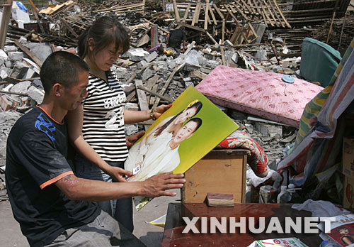 5月19日,虽然相框损坏了,夫妻俩还是仔细地把结婚照擦拭干净。 四川省什邡市蓥华镇仁和村三组的梁正彬一家很幸运,大地震发生时,包括老父母和年幼女儿在内的全家5口人都跑出了轰然倒塌的房屋。“平安就是福!”他们默默收拾废墟中的家,准备重建家园。