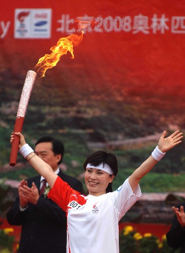 7月28日,第一棒火炬手李瑞英在起跑仪式上高举火炬。当日,北京奥运圣火在河南省安阳市传递。 新华社记者 岳月伟 摄