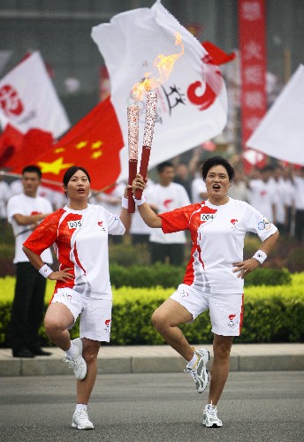 7月28日,火炬手张美瑛(右)与下一棒火炬手张峻英交接后合影。当日,北京奥运圣火在河南省安阳市传递。 新华社记者 邢广利 摄