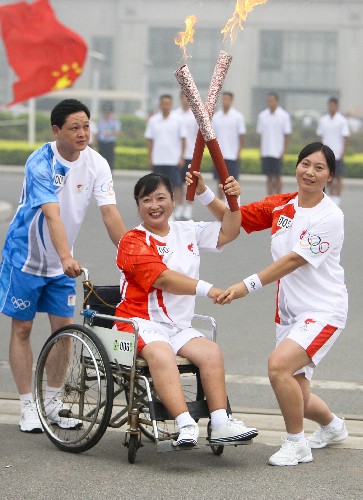 7月28日,火炬手张峻英(右)与下一棒火炬手贾红交接。当日,北京奥运圣火在河南省安阳市传递。 新华社记者 邢广利 摄