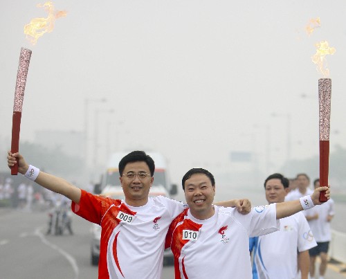 7月28日,火炬手王顺启(左)与下一棒火炬手武宏交接后合影。当日,北京奥运圣火在河南省安阳市传递。 新华社记者 邢广利 摄
