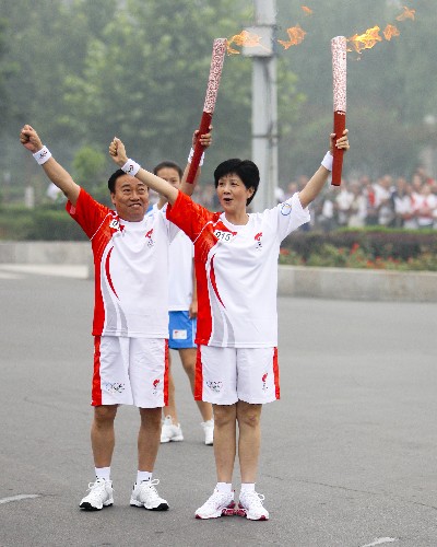 7月28日,火炬手李建安(右)与下一棒火炬手杨文周交接后合影。当日,北京奥运圣火在河南省安阳市传递。 新华社记者 邢广利 摄