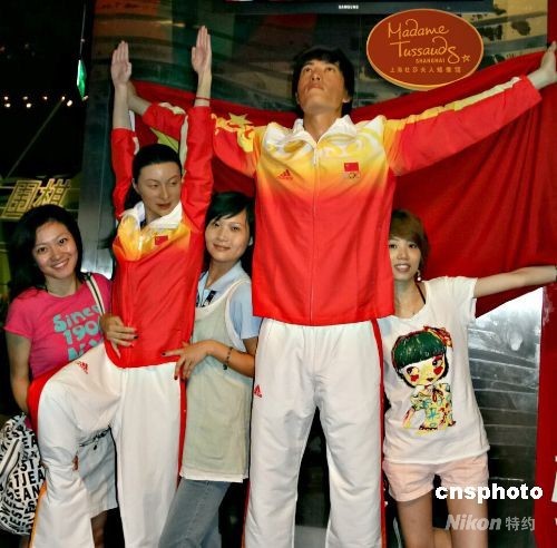 7月29日,上海杜莎夫人蜡像馆,游客与新换了装的刘翔、郭晶晶蜡像合影。该蜡像馆紧跟形势,在北京奥运会中国体育代表团领奖服公布后,新近为刘翔、郭晶晶进行了换装,立刻引来游客的好奇,纷纷驻足观看并上前与之合影留念。 中新社发 沈晨 摄