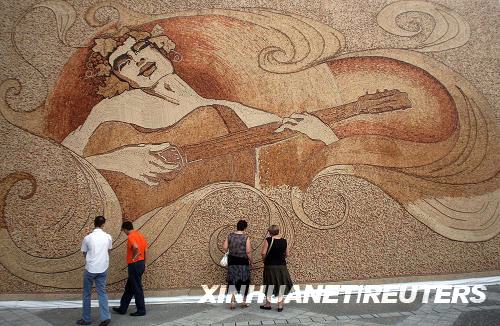 9月4日,观众在阿尔巴尼亚首都地拉那欣赏世界最大的软木镶嵌画。艺术家萨伊米尔·斯特拉蒂使用229764块形状颜色各异的软木塞在一块长12.94米、高7.1米的塑料背景板上创作了这幅名为《戴着葡萄花冠的罗密欧在海浪和阳光中弹琴起舞》的镶嵌画。