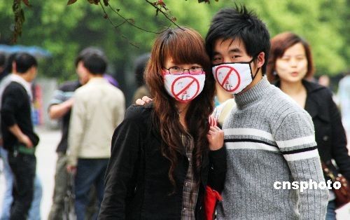 4月29日,湖北恩施街头,一对大学生情侣口戴自制的防猪流感口罩,吸引了许多行人观看。据悉,为了倡导良好个人卫生习惯,两位大学生自制防猪流感口罩,以警示路人。中新社发陈地长 摄