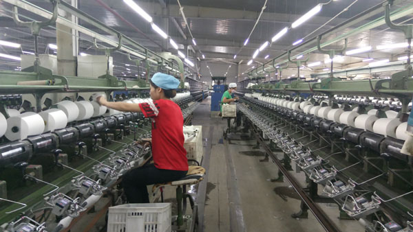 2017年12月14日,黑龙江金品格纺织公司女工正在生产车间纺纱作业.