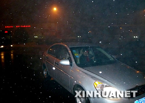 12月28日,在北京一条道路上,车辆冒着雾霾和小雪行驶