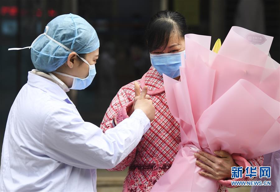 1月29日,在重庆三峡中心医院,主管医生向治愈患者蒋某送花表示祝贺.